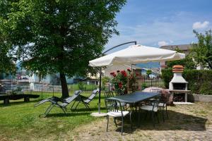 a table and chairs under an umbrella in a yard at Attic House Mountain Lake Iseo Hospitality in Bossico