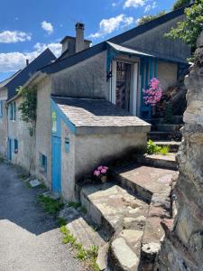 a small house with a blue door and stairs at La Maison du Patou in Cadéac