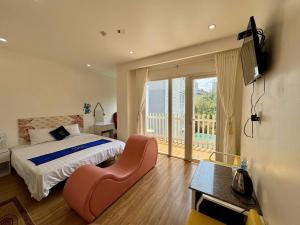 a bedroom with a bed and a chair and a balcony at Nice Hotel Buôn Ma Thuột in Buon Ma Thuot