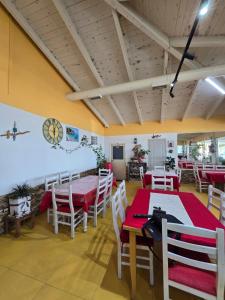 a dining room with tables and chairs and a clock on the wall at Hotel Restorant Genti Peshkatari in Orikum