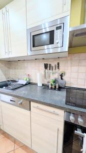 a kitchen with white cabinets and a microwave at Geräumiges & helles Apartment nahe Leipzig in Böhlen +10 photos