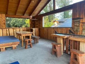 a patio with tables and benches and a pool table at Hostel Raíz Del Pillán in Pucón