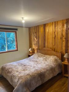 a bedroom with a large bed with wooden walls at Hostel Raíz Del Pillán in Pucón