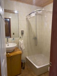 a bathroom with a tub and a sink and a bath tub at Hostel Raíz Del Pillán in Pucón +23 photos