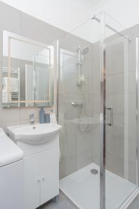 a white bathroom with a sink and a shower at Captain's Quarters - with Terrace and Parking near Lake Balaton in Keszthely
