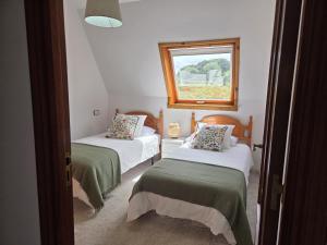 two beds in a room with a window at Mar de Laxe Vistas al mar y Costa da Morte in Cabana de Bergantiños