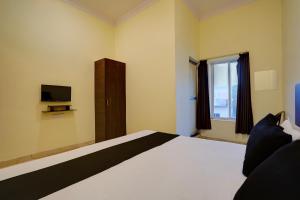 a bedroom with a bed with a television and a window at Hotel O Maa JP Tower in Jabalpur