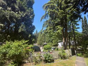 a garden behind a fence with trees in the background at Cozy EnSuite No Pets Allowed in Burnaby