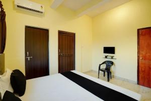 a bedroom with a bed and a chair and a television at Hotel O Maa JP Tower in Jabalpur