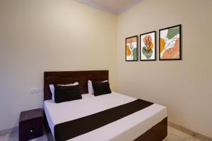 a bedroom with a bed with three pictures on the wall at Hotel O Maa JP Tower in Jabalpur