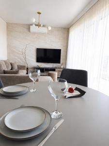 a dining room table with plates and wine glasses at Kregždžių apartamentai in Šventoji