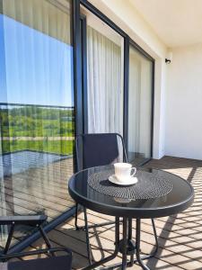 a coffee cup sitting on a table on a balcony at Kregždžių apartamentai in Šventoji