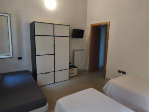 a bedroom with two beds and a cabinet and a television at Ostello di Montefiorino in Montefiorino