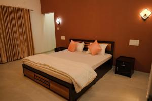a bedroom with a large bed with orange pillows at The Calm County Homestay in Mānantoddy +69 photos