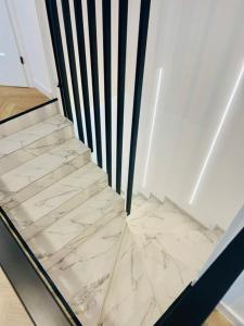 a staircase with marble floors and a black and white railing at Apartament Drohiczyńska in Siemiatycze