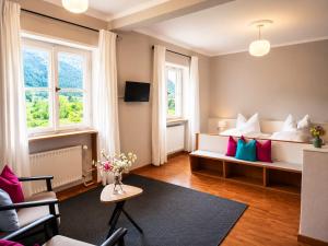a living room with a bed with colorful pillows at Pension Villa Bergkristall in Eschenlohe
