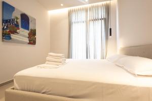 a white bedroom with a large bed with towels on it at Aria apartment 2 in Dhërmi