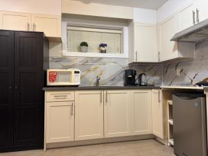 a kitchen with white cabinets and a microwave at Garden suite in Vancouver