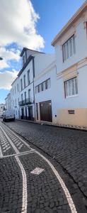 a cobblestone street with white buildings and a building at Canto do Atlântico Loft (City Centre) in Ponta Delgada