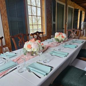 a long white table with blue napkins and flowers on it at Peach Grove House in Warwick