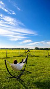 a person laying in a hammock in a field at Bell-tent Rosa met uitzicht in Hensbroek +7 photos