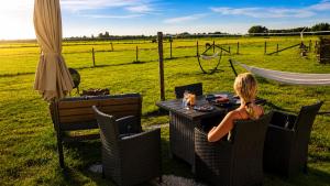 a woman sitting at a table in front of a field at Bell-tent Rosa met uitzicht in Hensbroek