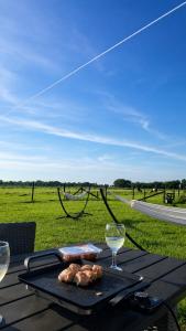 a table with a plate of meat and two glasses of wine at Bell-tent Rosa met uitzicht in Hensbroek