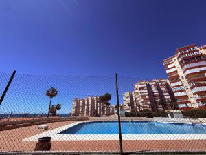 a fence in front of a swimming pool with buildings at Brisa Mediterránea Torrox Costa in Torrox Costa