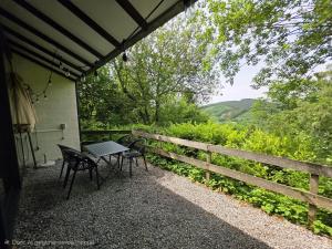 a table and chairs on a porch with a fence at Slow Stay Coo in Stavelot