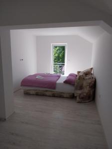 a bed in a white room with a window at Apartmani Lohovo 2 in Lohovo