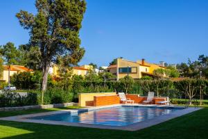 a swimming pool in a yard with chairs and a house at Villa Fernandos in Praia de Mira