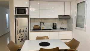 a kitchen with white cabinets and a table and chairs at Dar Lebharr Kélibia in Kelibia +23 photos