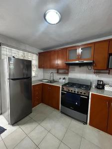 a kitchen with wooden cabinets and a stainless steel refrigerator at Comfortable house with an excellent location in Veracruz +8 photos