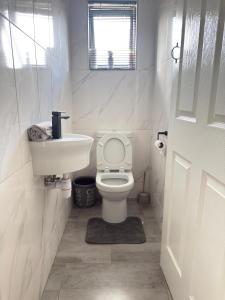 a white bathroom with a toilet and a sink at Palmview in Bulawayo