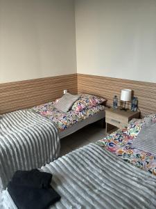ein Schlafzimmer mit zwei Betten und einem Tisch mit Lampe in der Unterkunft Łowicka22 in Piątek