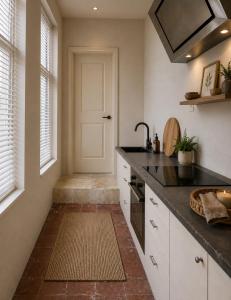 a kitchen with white cabinets and a black counter top at Fontaine Studio Appartement in Ribérac