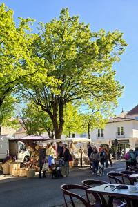 a group of people at an outdoor market with a tree at Fontaine Studio Appartement in Ribérac