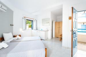 two beds in a white room with a kitchen at Fiore Di Mare Studios in Lassi