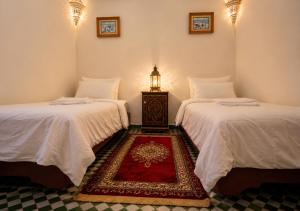 a room with two beds and a table with a lamp at Dar Albanin in Fez