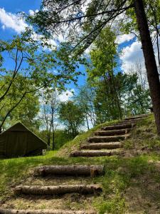 a group of logs on a hill with a tent at Sanovia Glamping in Reczpol
