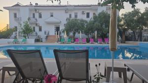 a hotel with chairs and an umbrella next to a swimming pool at Bena pansiyon in Fethiye