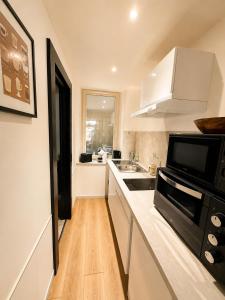 a kitchen with white cabinets and a black microwave at L'Instant Saint-Epvre Charm & Old Town in Nancy +9 photos