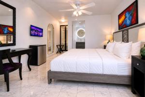 a bedroom with a white bed and a desk at Coral Princess Hotel in San Juan