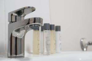 a bathroom sink with a faucet and some bottles at The Marlowe in Southport +125 photos