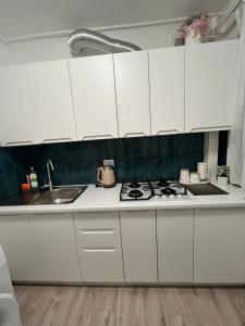 a kitchen with white cabinets and a sink and a stove at Mykolaichuka in Chernivtsi +16 photos