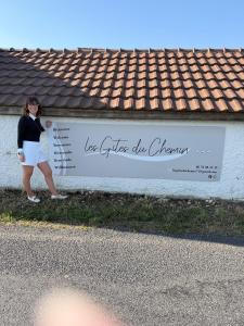 a woman is standing in front of a sign at Les gîtes du Chemin Le Compostelle in Paray-le-Monial