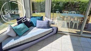a couch with pillows sitting in a room with a window at Maison 5 chambres, 3 SdB, proche plage in Arzon +22 photos