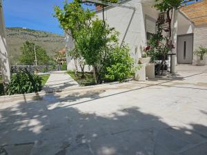 a walkway with trees and a house and a building at Olive Roots Yard House in Trebinje