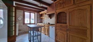 a kitchen with wooden cabinets and a stool in it at Le gîte des Sorbiers in Charmes-lès-Langres +11 photos