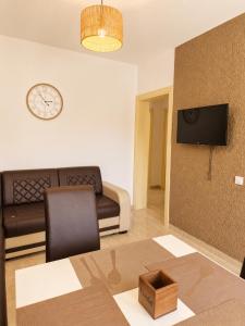 a living room with a couch and a clock on the wall at Monte Liza Apartments in Dobra Voda